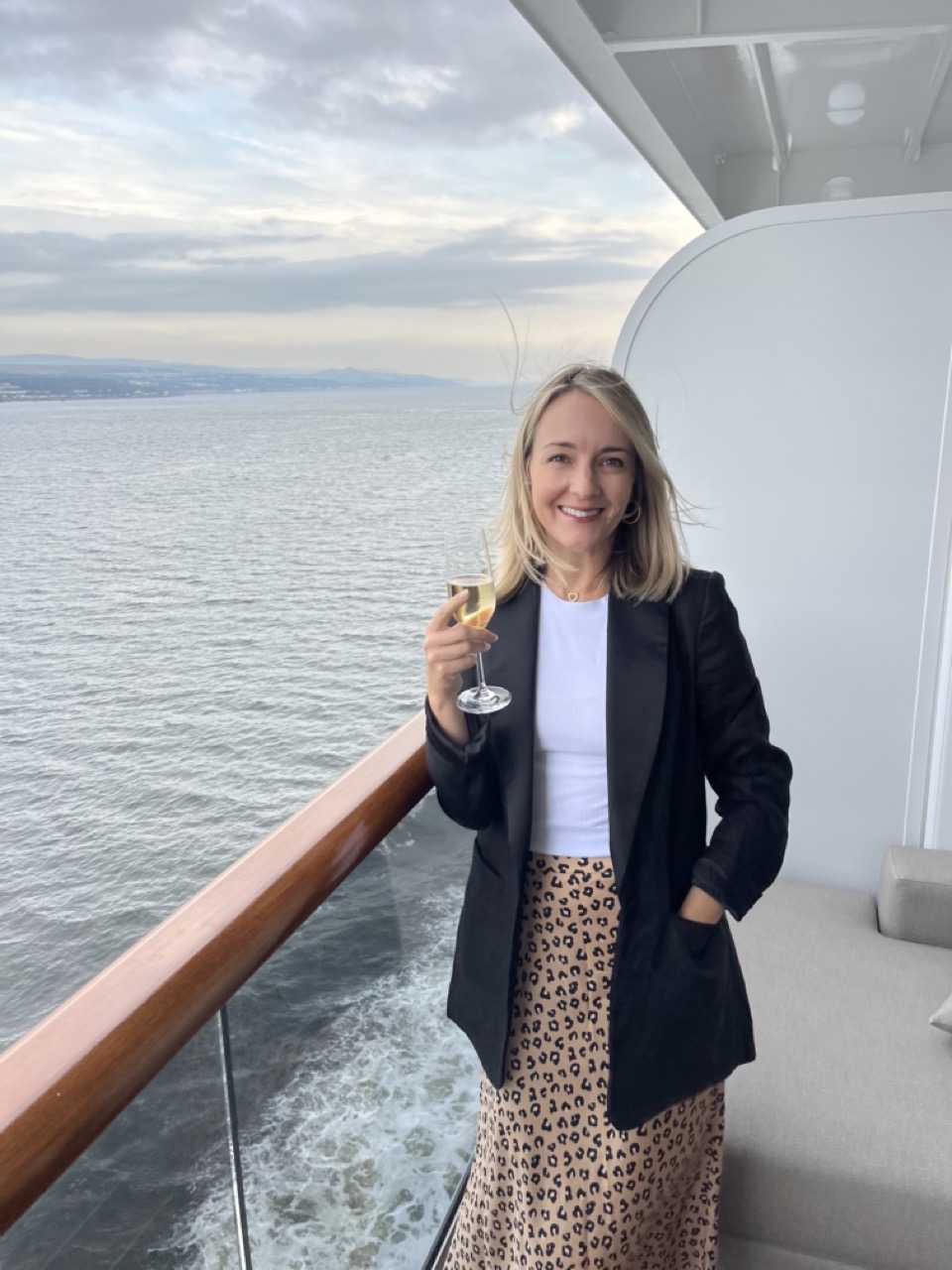 Woman standing on cruise stateroom terrace holding glass of champagne